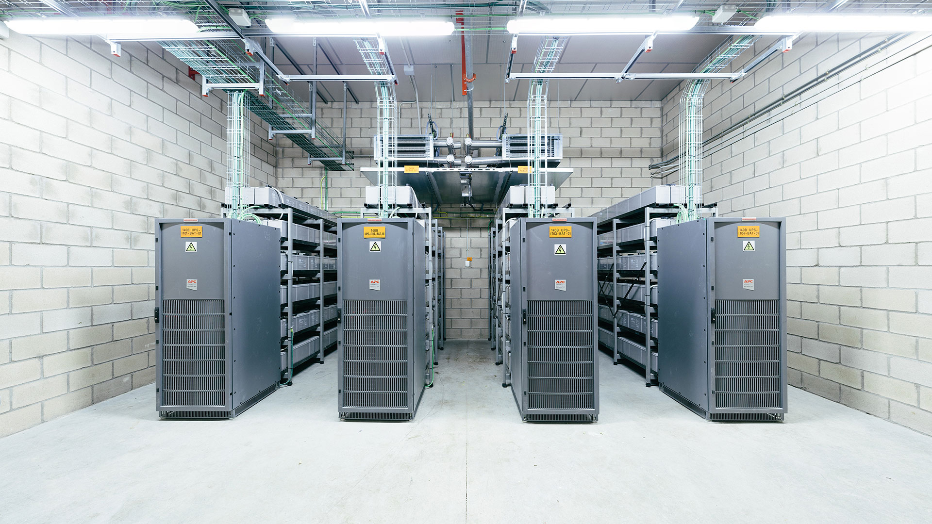 A data centre corridor, tall server racks on either side receding to a vanishing point